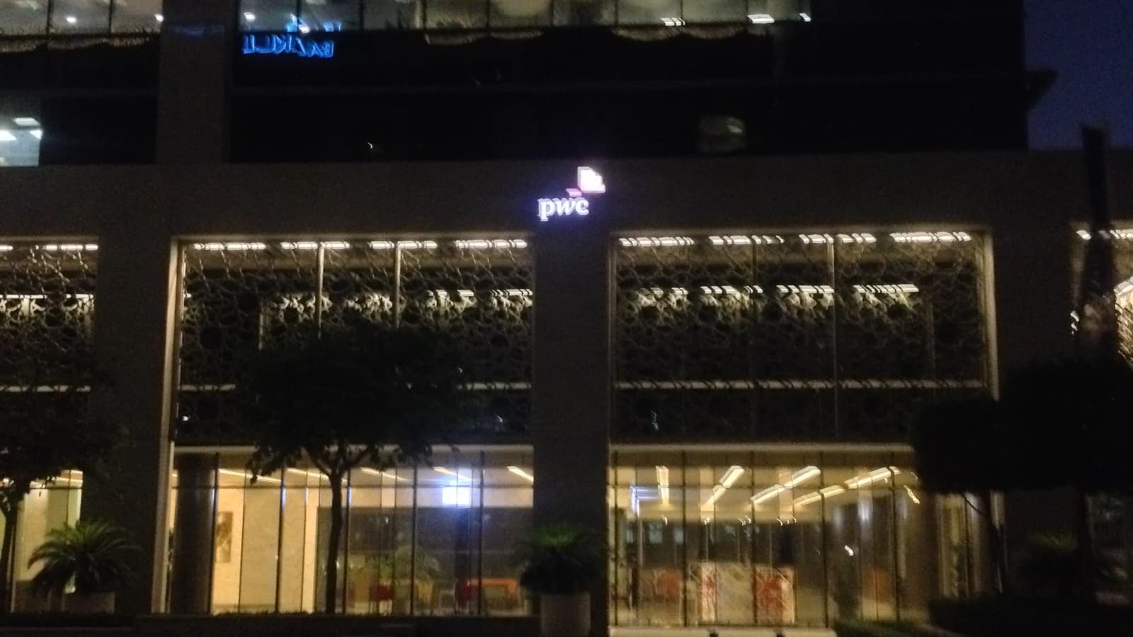 Ночной вид офиса PwC в Emaar Square в Дубае с подсвеченным логотипом компании.