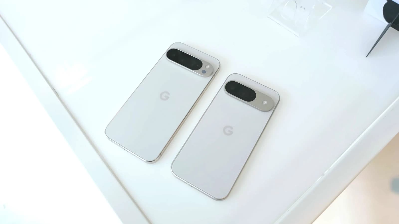 Два белых смартфона Google Pixel лежат задними панелями вверх на светлом столе