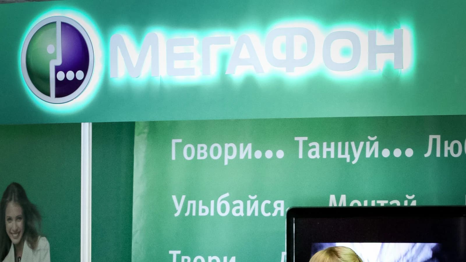 Интерьер салона связи «МегаФон» с фирменной вывеской и сотрудницей