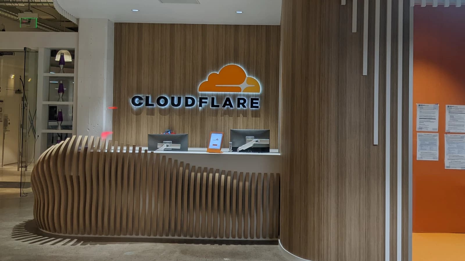 Стойка ресепшена в офисе с подсвеченной вывеской Cloudflare