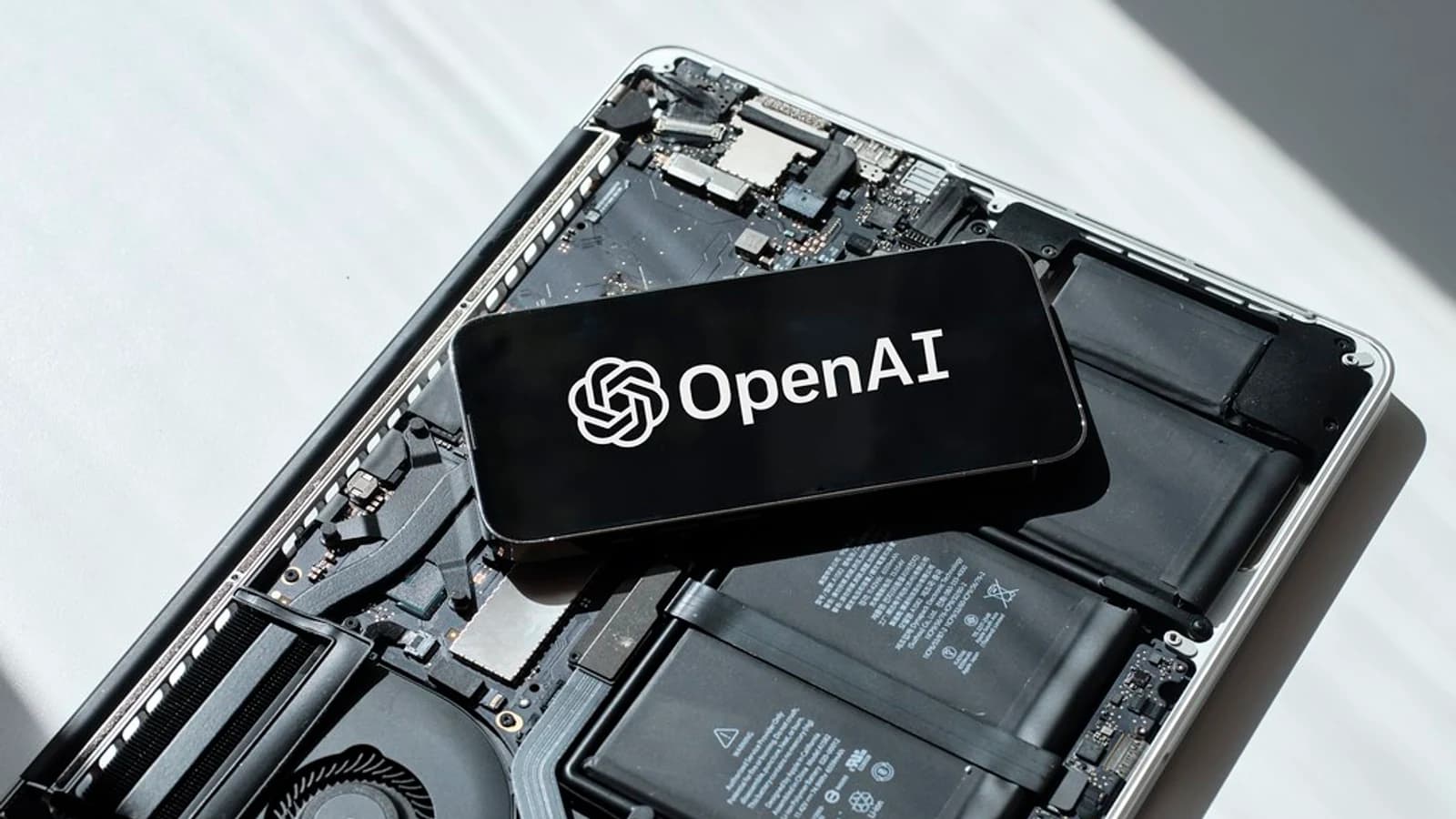 Смартфон с логотипом OpenAI лежит на разобранном ноутбуке